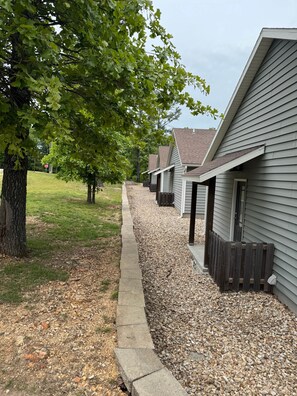 A row of single-story houses with a gravel pathway and a tree-lined driveway.