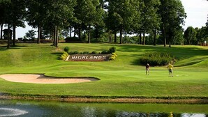 A golf course with a sign reading "HIGHLANDS" and a pond in the foreground.