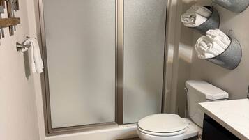 Une salle de bain avec une douche, des toilettes et des porte-serviettes.
