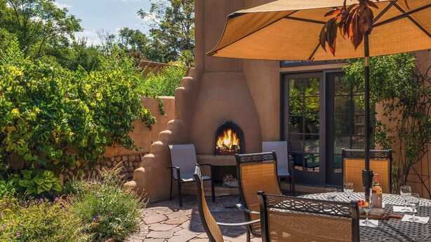 Une terrasse extérieure avec un foyer, des sièges et une table dressée pour les repas.