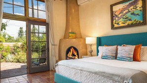 Une chambre avec un grand lit, une cheminée et une vue sur l’extérieur.