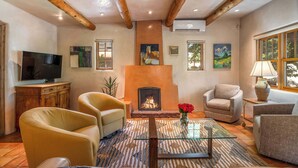 Un salon chaleureux avec une cheminée, des sièges confortables et des œuvres d’art accrochées aux murs.