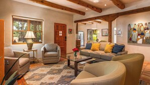 Un salon spacieux doté d’une grande fenêtre, de poutres apparentes et d’un coin salon confortable avec un canapé et des fauteuils.