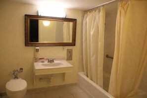A bathroom with a sink, mirror, toilet, and bathtub. - Bedford plaza hotel (Bedford)