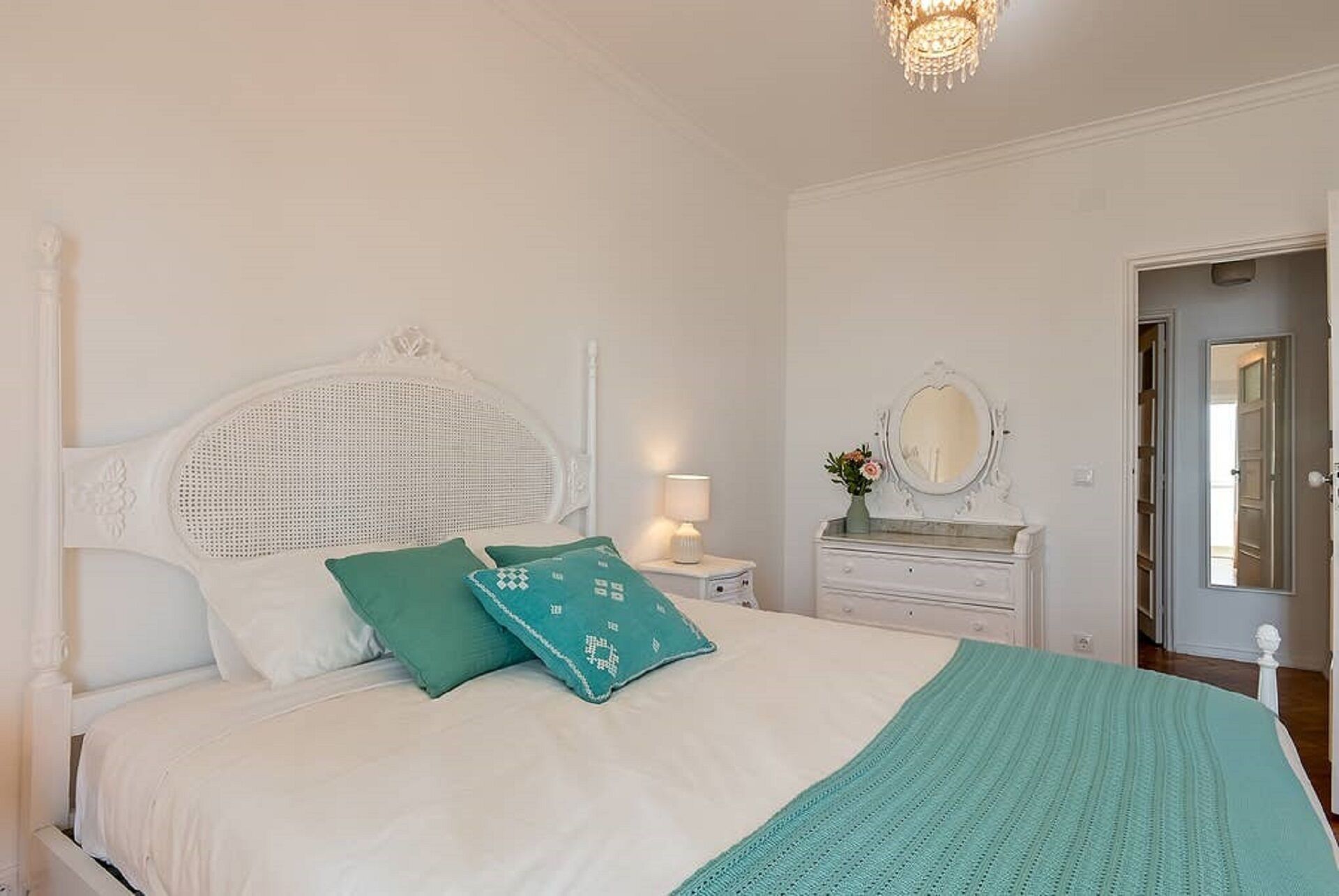 A bedroom with a bed, a nightstand, a dresser, a mirror, and a door.
