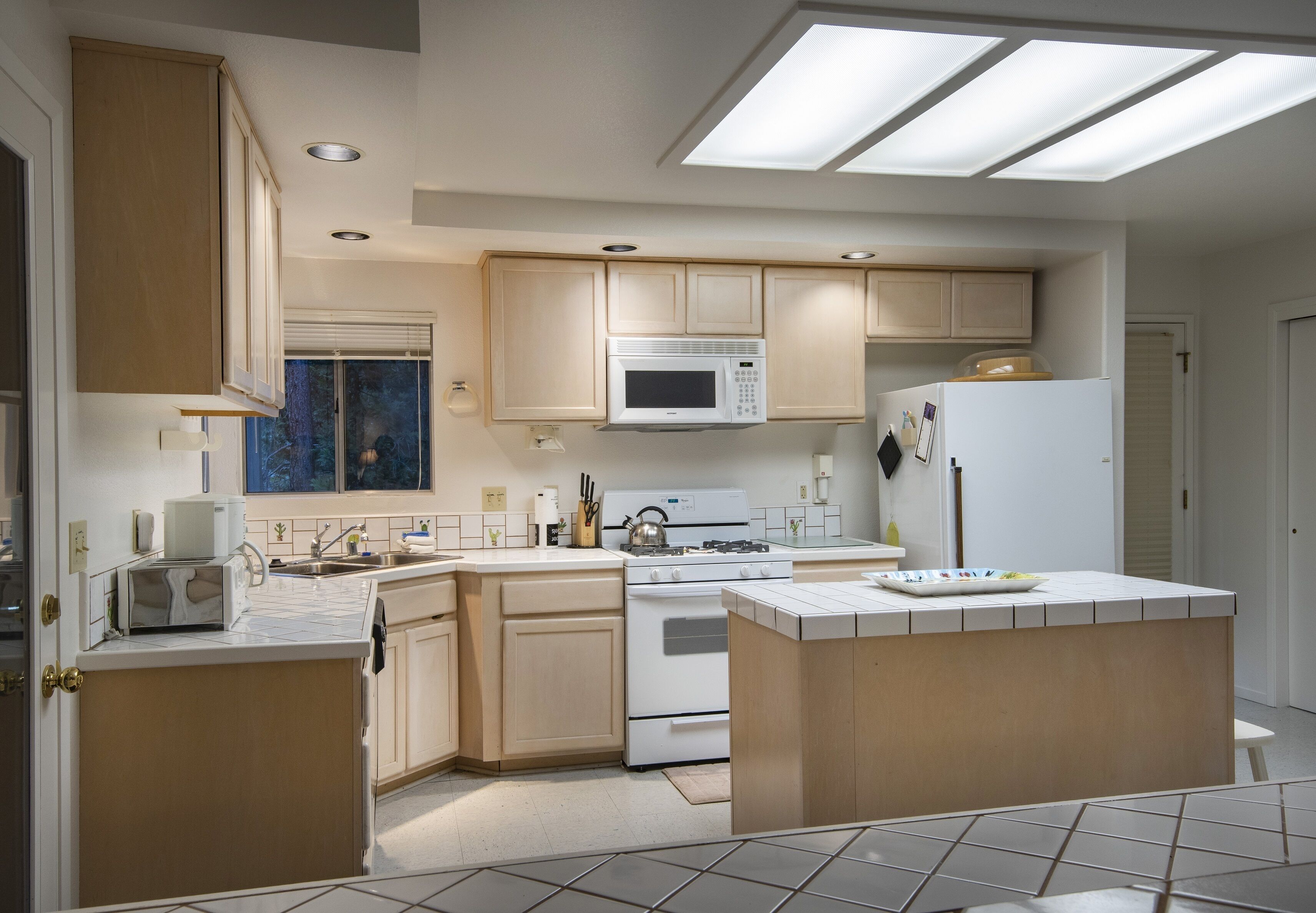 A modern kitchen with a central island, built-in microwave, and gas stove.