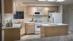 Una cocina moderna con una isla central, microondas integrado y estufa a gas.