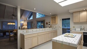 Una cocina moderna con una isla central, iluminación colgante y vistas al exterior.