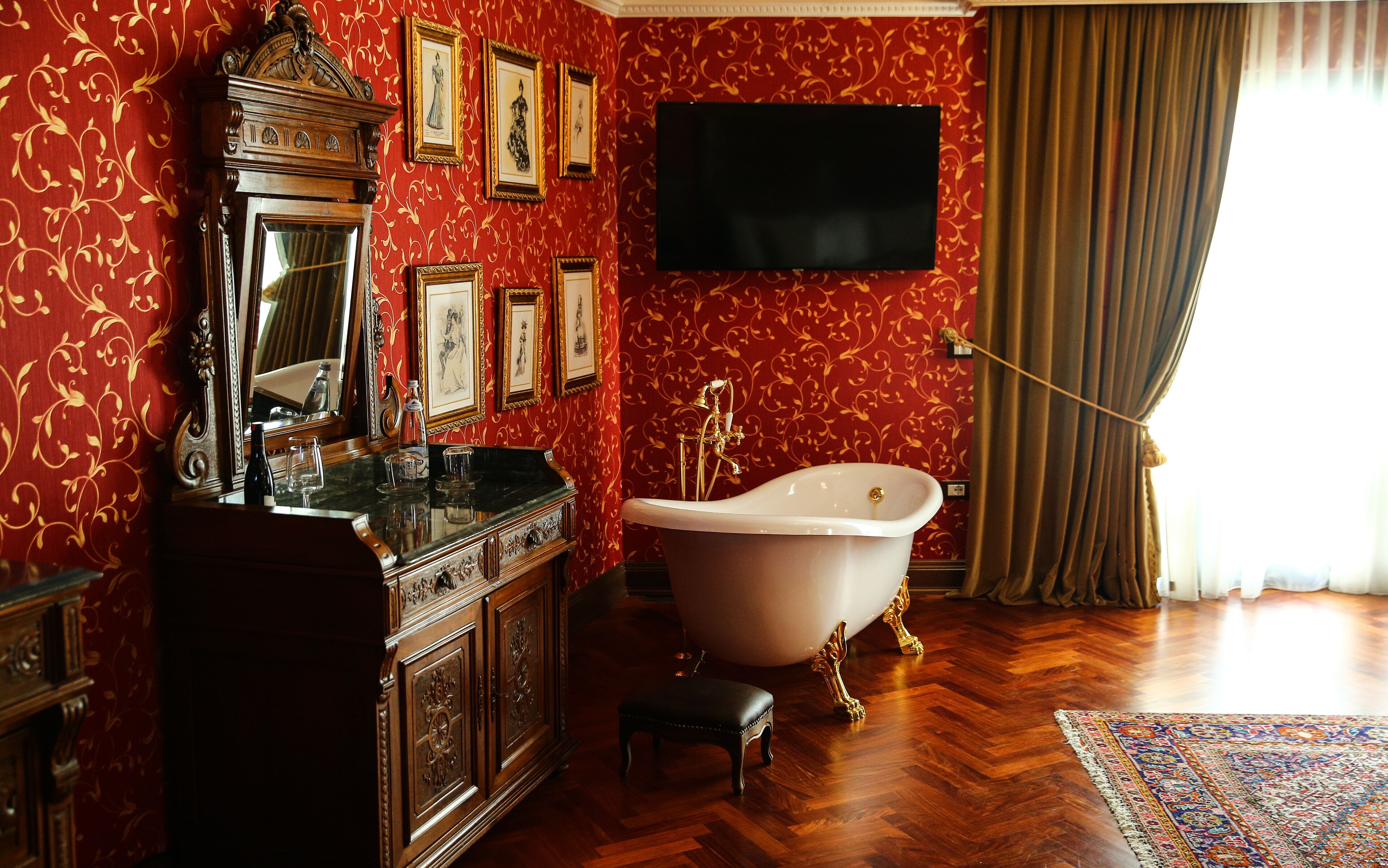 A bathroom with a freestanding bathtub, a vanity with a mirror, and framed artwork on the wall.