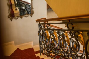 A staircase with ornate metal railings and a red and white checkered floor.