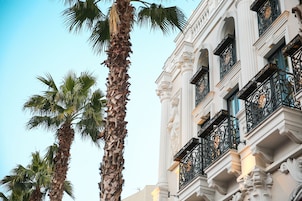 Un edificio con balcones ornamentales y palmeras.