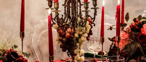 Una mesa adornada con velas rojas, un candelabro y una variedad de frutas y flores.