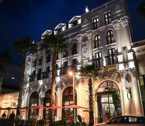 A grand hotel with ornate architecture, large arched entrances, and a well-lit facade. - Hotel Epidamn (Durrës)