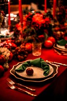 Una mesa dispuesta con un mantel verde, un adorno rojo y un vaso de agua.