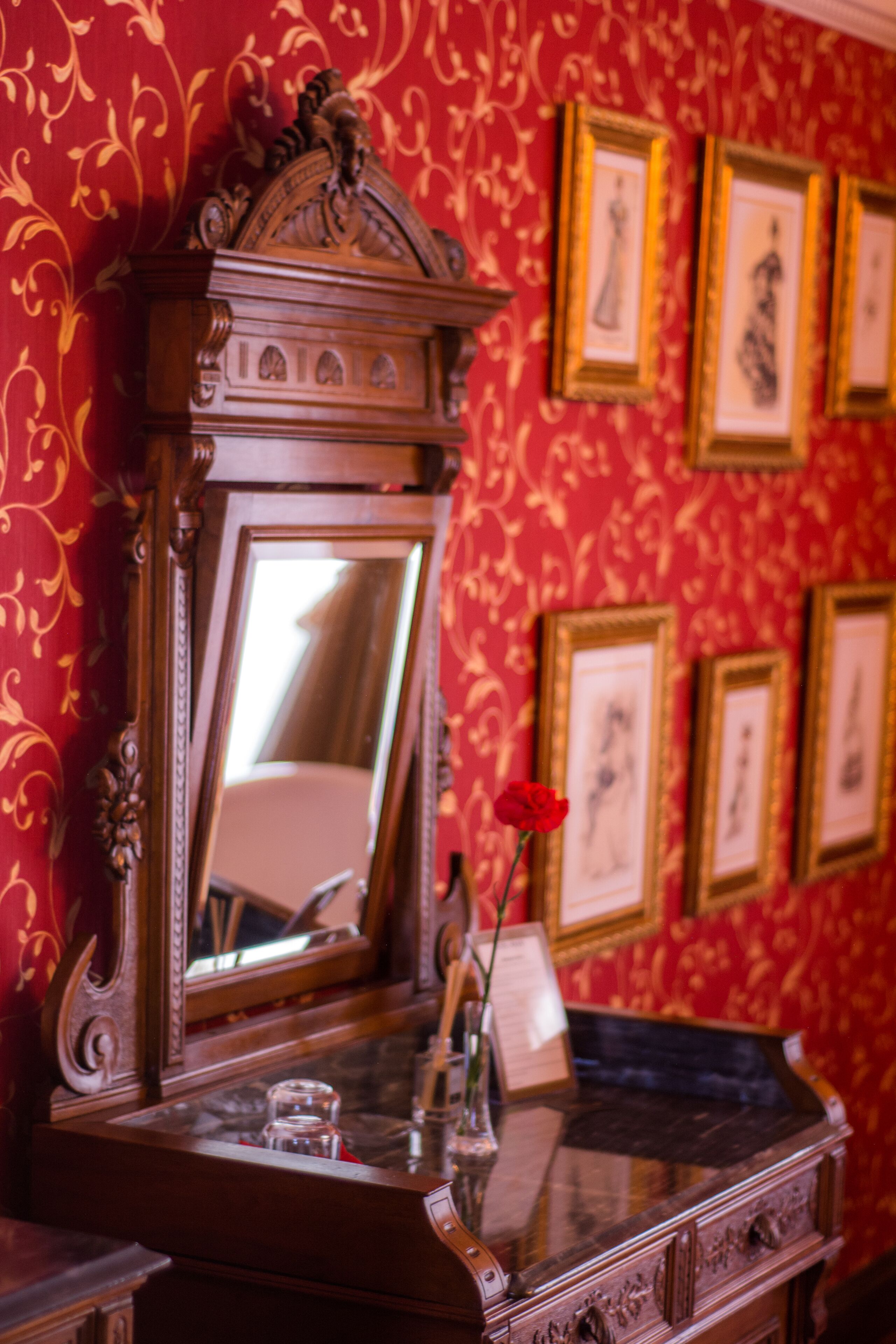 A room with a wooden dresser, a mirror, and framed pictures on the wall.