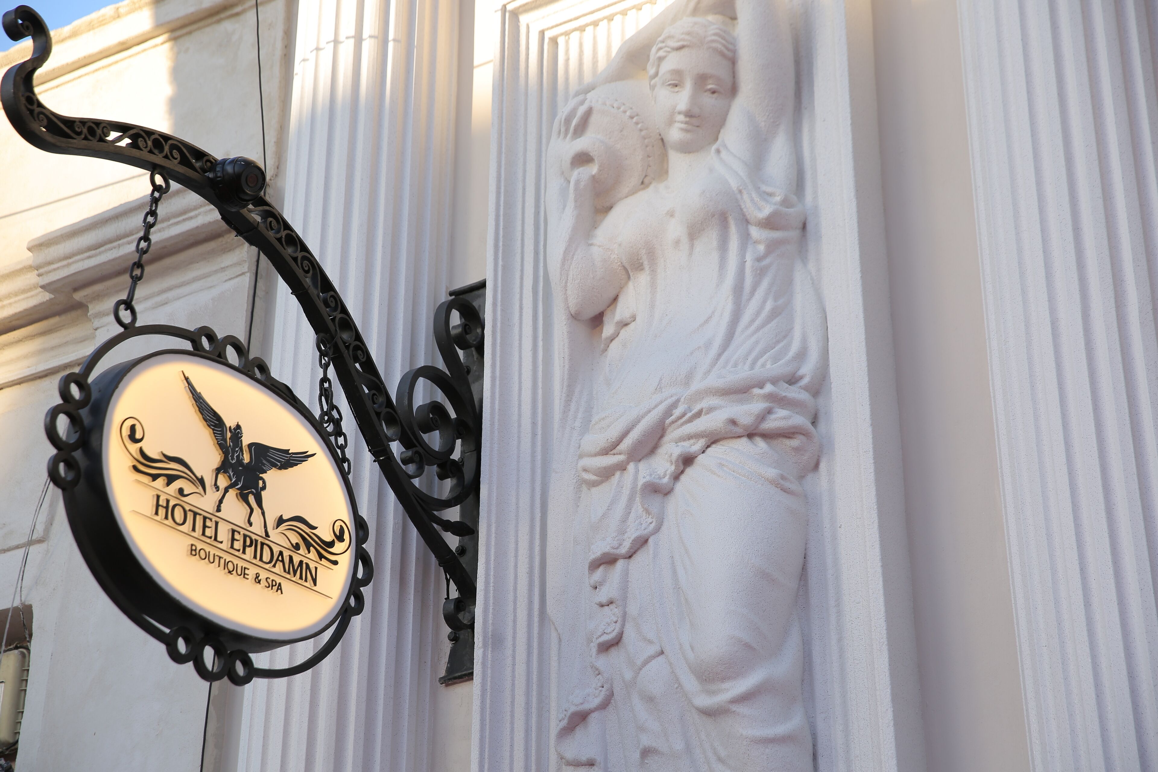 Placa de hotel com emblema de um cavalo alado e o nome 'HOTEL EPIDAMN BOUTIQUE & SPA'.