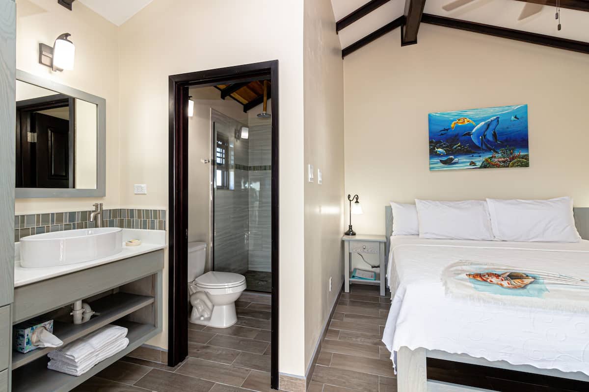 A bathroom with a sink, toilet, and shower. There is a painting of a dolphin on the wall.