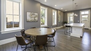 Una cocina amplia con una isla central, ventanas grandes y un comedor con seis sillas.
