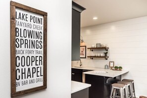 Une cuisine dotée d’un plan de travail blanc, de meubles de rangement noirs et d’un espace bar-grill.