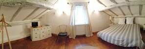 A bedroom with a bed, a chair, a dresser, and a television. - Douvilla (Douville)