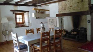 Un coin repas avec une table et des chaises en bois, une fenêtre, une cheminée et une lampe.