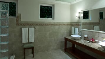 Un baño con un espejo grande, un lavabo y una silla.