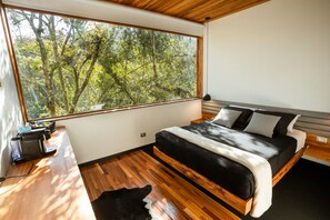 A bedroom with a large window, a bed, a wooden desk, and a black and white rug. - Winter Suites Campos do Jordão (Campos do Jordão)