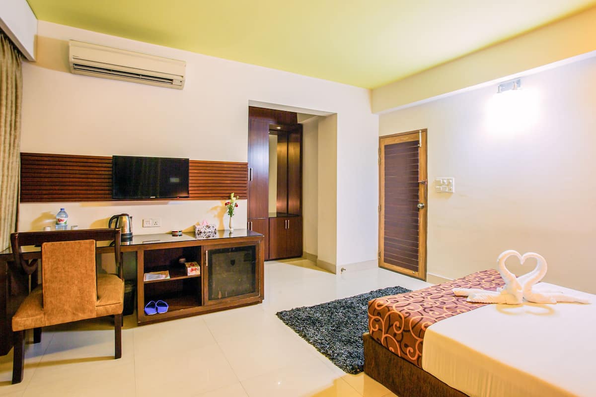 A hotel room with a bed, a TV, a desk, and a wardrobe.