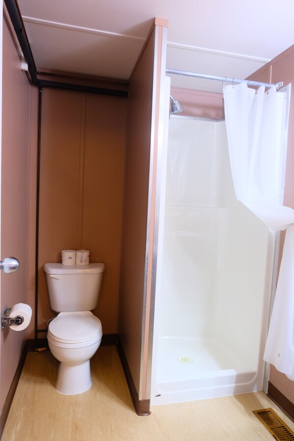 A small bathroom with a toilet, a shower, and a door.