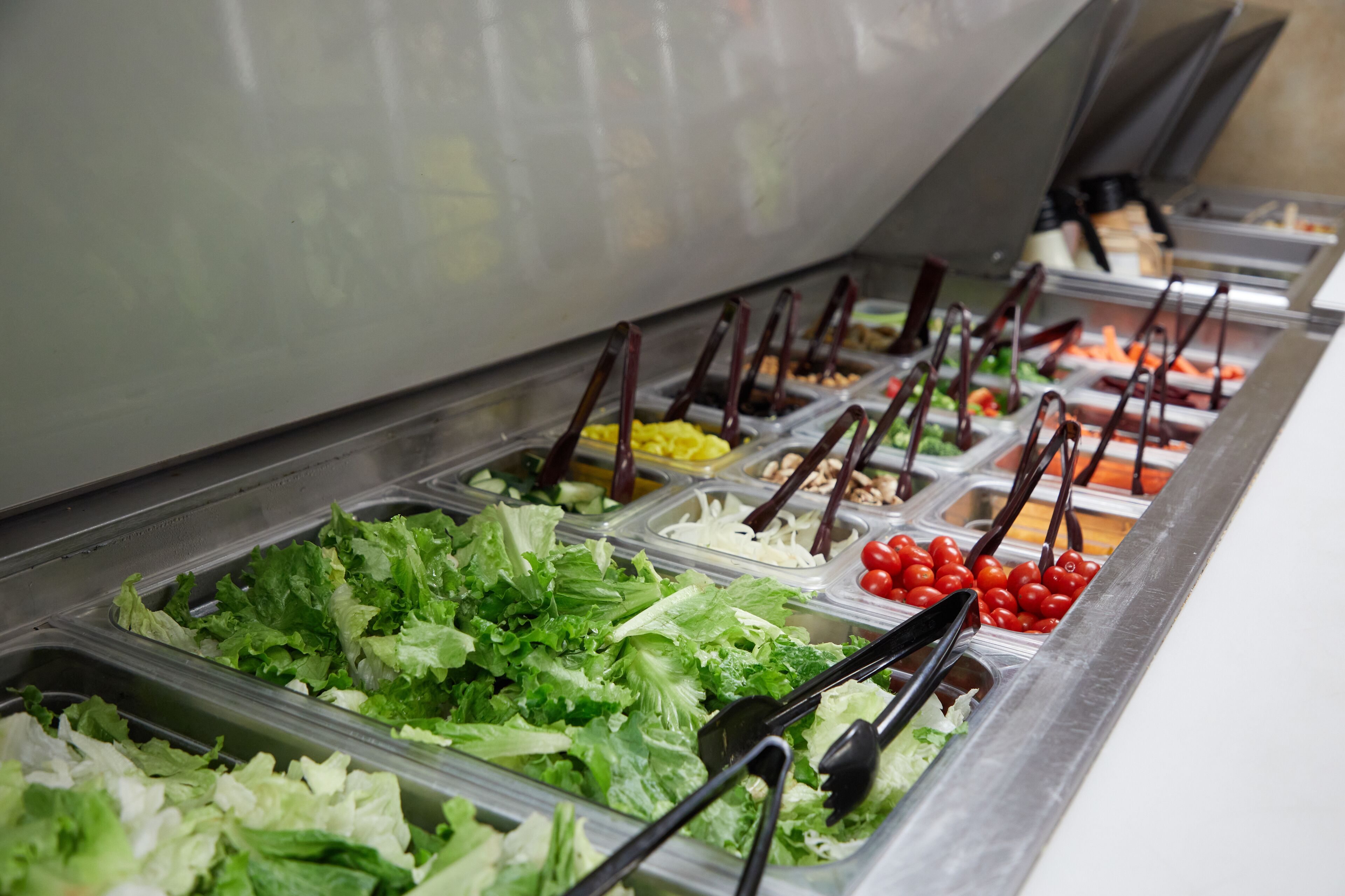 Un buffet proposant une variété de plats, notamment des salades, des légumes et des fruits.