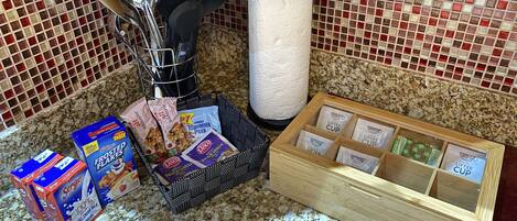 A kitchen counter with various food items, a paper towel holder, and a spice rack.