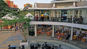 Un espacio de comedor al aire libre con varios niveles, mesas y sillas, rodeado de edificios.
