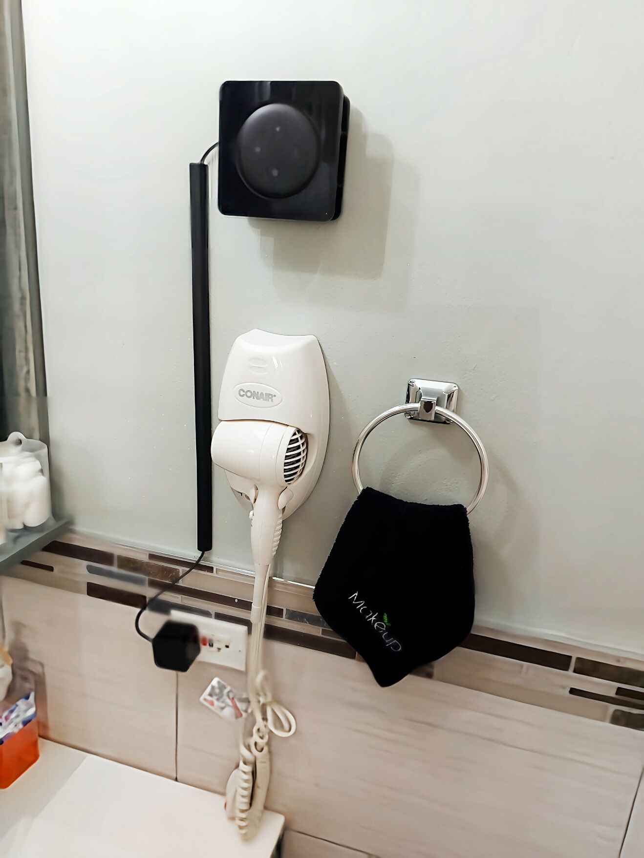 A hairdryer, a black speaker, and a black hair mask on a wall.