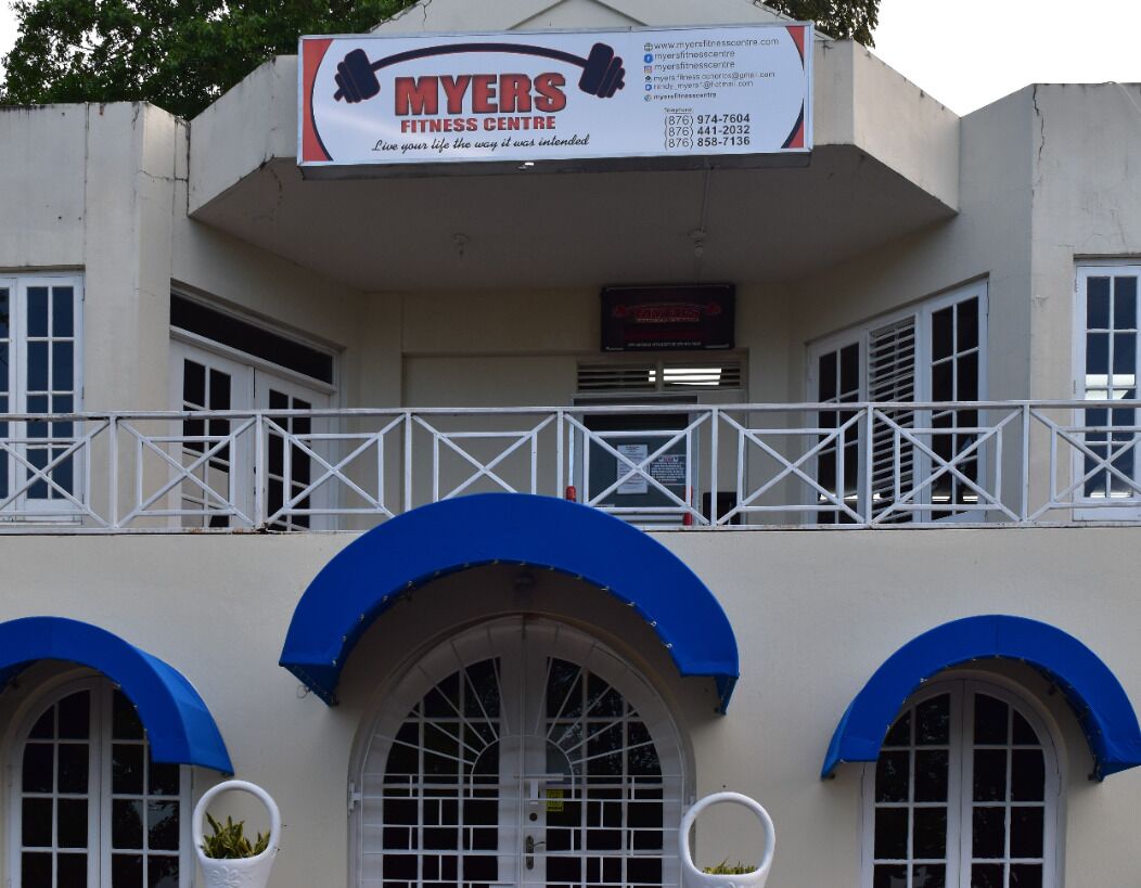 A building with a sign for 'MYERS FITNESS CENTRE' and a balcony with a railing.