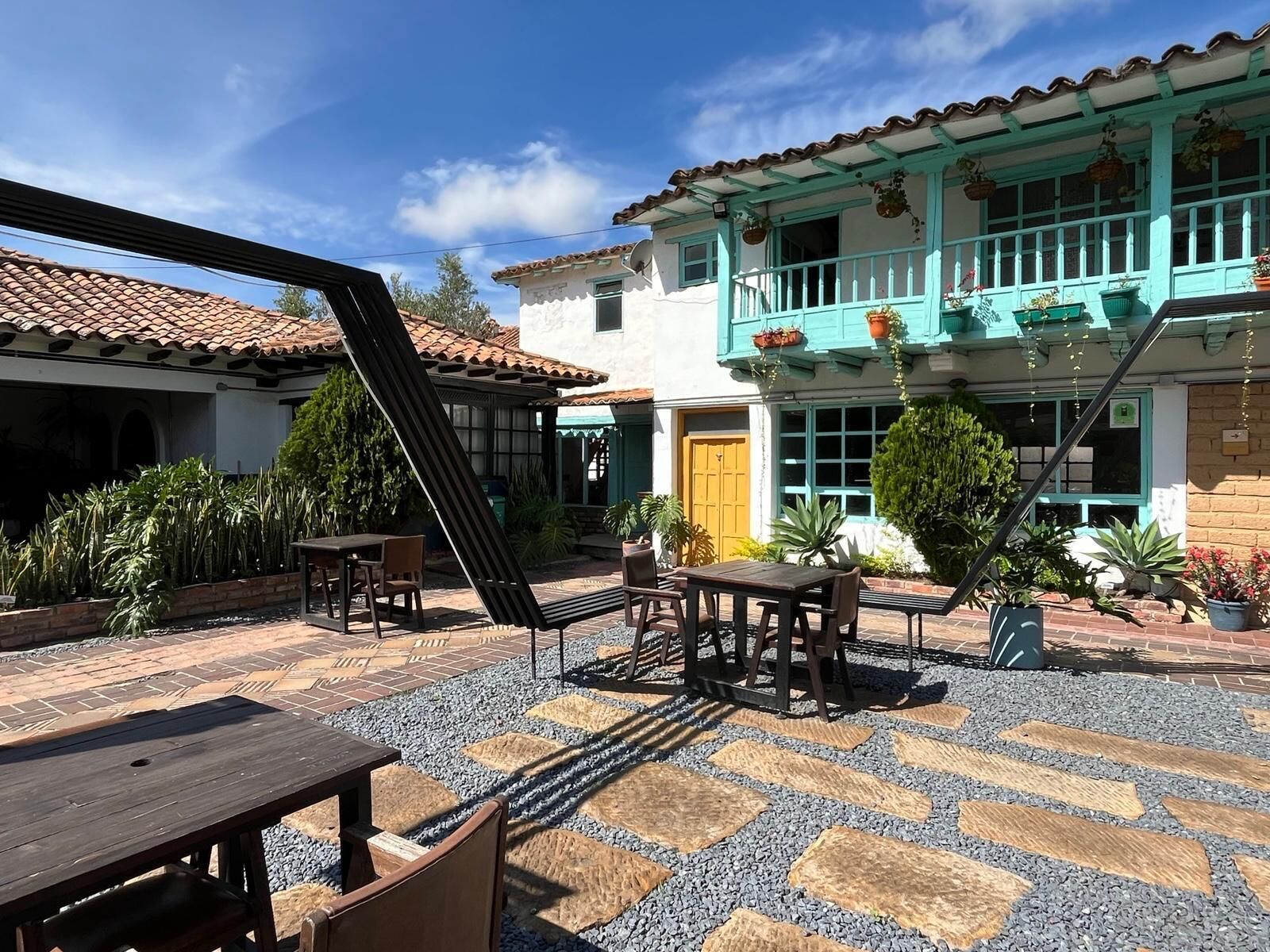 Un patio con mobiliario exterior, una escalera y un edificio con tejado de baldosas y adornos azules.