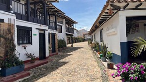 A cobblestone street lined with white buildings with black balconies and tiled roofs. -  Hotel Aceitunos (Villa de Leyva)