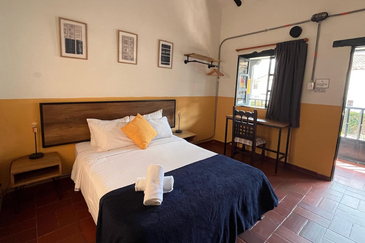 Une chambre d’hôtel avec un lit, une chaise, une petite table et une fenêtre donnant sur un paysage agréable.