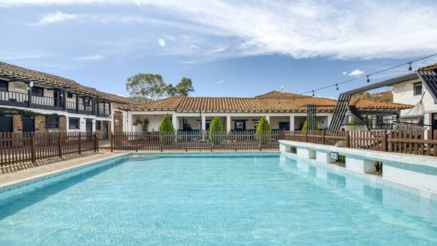 A swimming pool with a tiled deck, surrounded by buildings with a traditional architectural style. -  Hotel Aceitunos (Villa de Leyva)