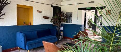 A blue sofa, a brown chair, and a yellow door in a room with tiled flooring and plants.
