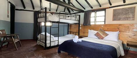 A room with bunk beds, a desk, and a chair.