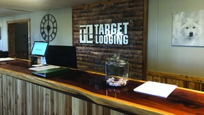 A reception desk at Target Lodging with a wooden counter, a clock, and a framed picture on the wall. - Target Hospitality-Odessa West Lodge (Notrees)