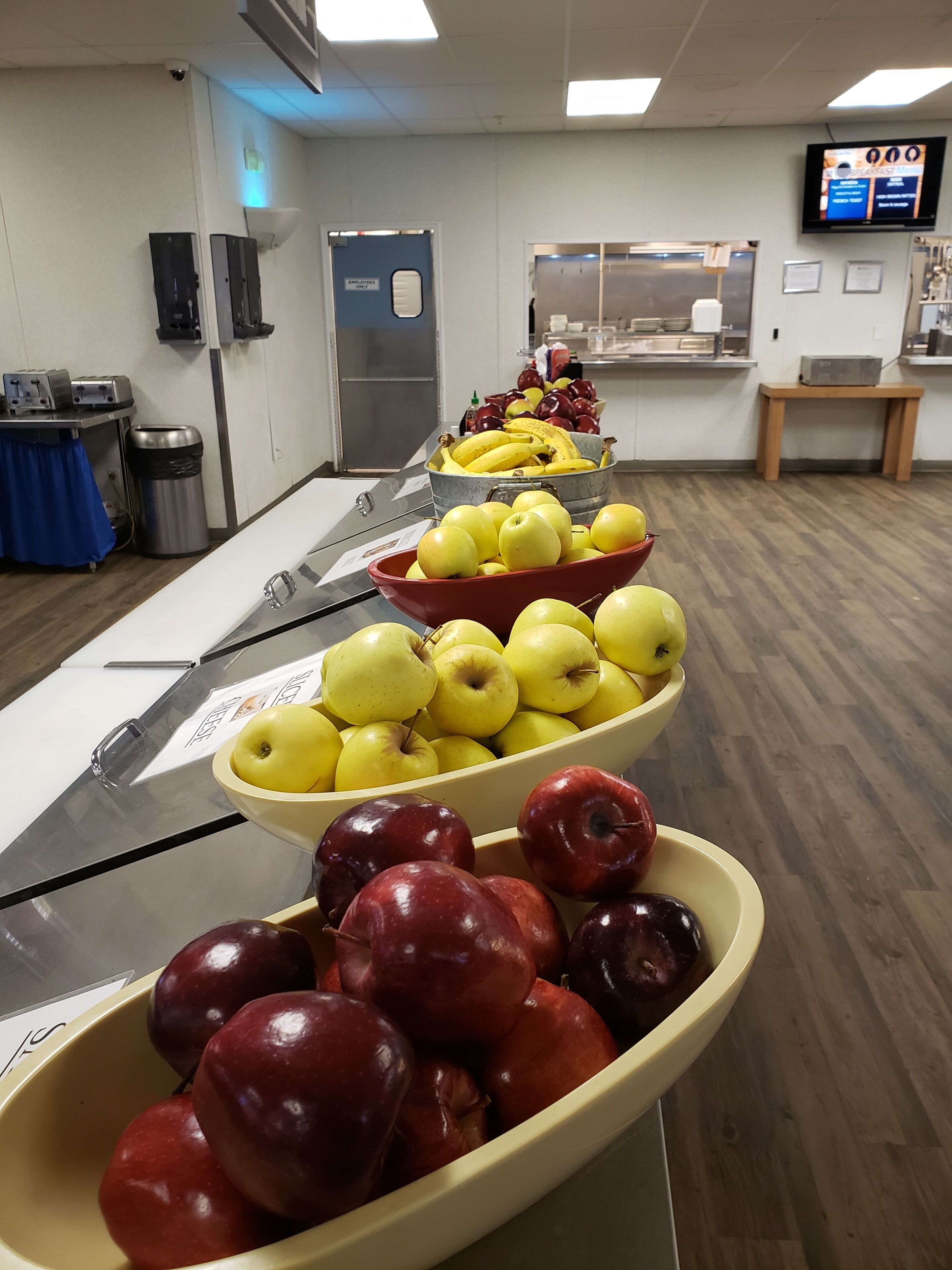 A buffet setup with bowls of apples and bananas.