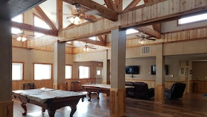 A spacious room with wooden floors, a pool table, and ceiling fans. - Target Hospitality - Mentone Skillman Station Lodge (Mentone)