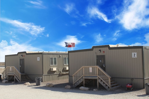Two portable buildings with numbered doors, a flag, and a small red wagon. - Target Hospitality - Mentone Skillman Station Lodge (Mentone)