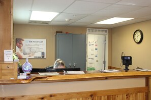 A reception desk with a clock, a security camera, and a sign for TH Assistant. - Target Hospitality - Mentone Skillman Station Lodge (Mentone)