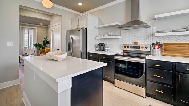 A modern kitchen with a central island, stainless steel appliances, and a hexagonal backsplash.