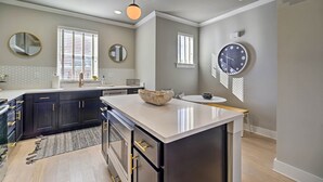 A modern kitchen with dark cabinets, a large island, and pendant lighting.