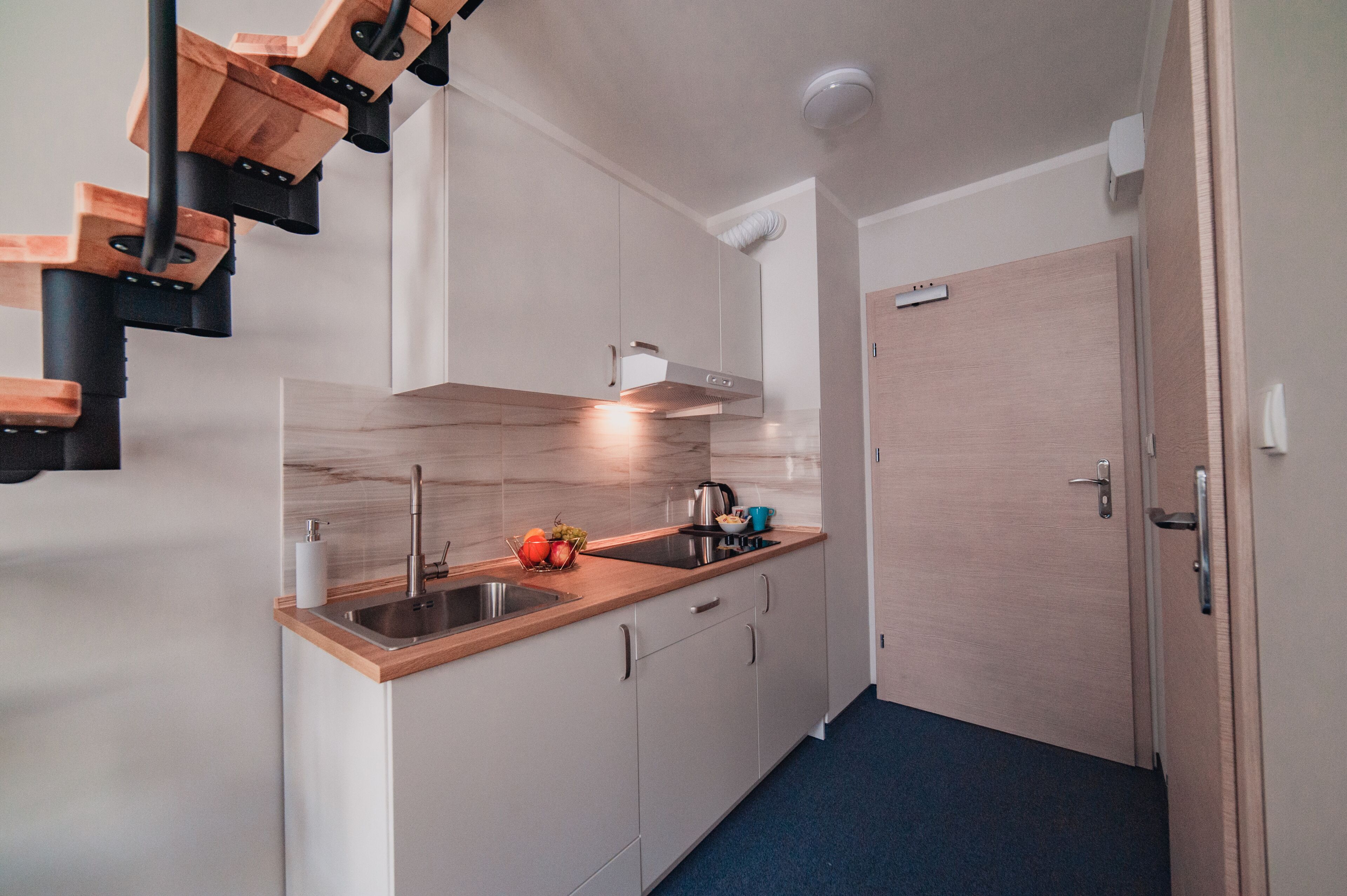 A compact kitchen with a wooden countertop, stainless steel sink, and a built-in oven.