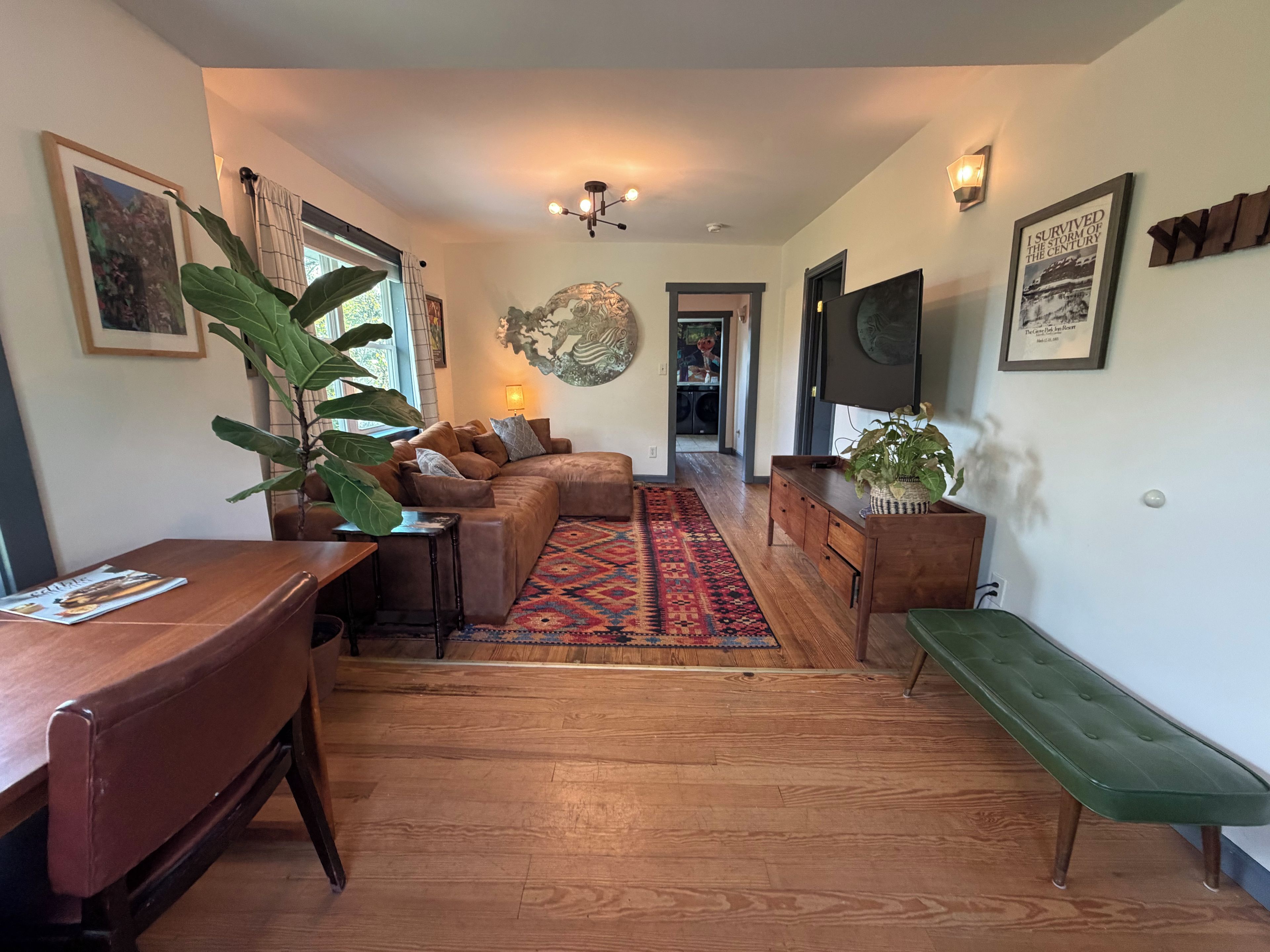 Een gezellige woonkamer met een modulaire bank, een houten salontafel, een vloerkleed met dessin en een televisietoestel.