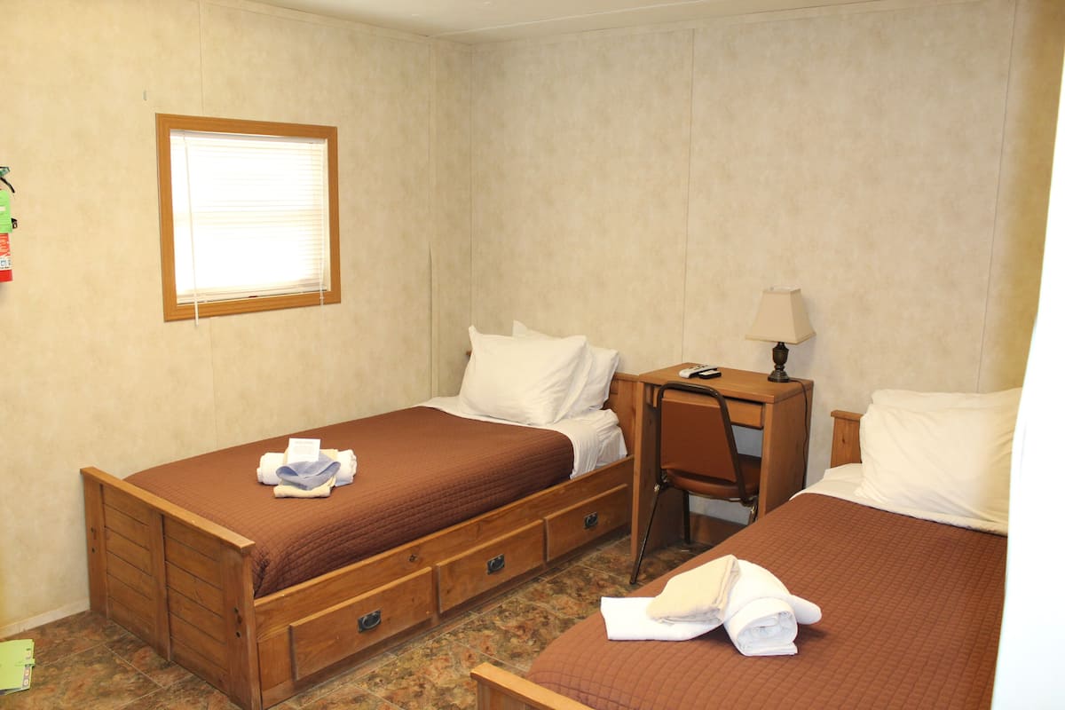 A bedroom with two beds, a desk, and a chair.